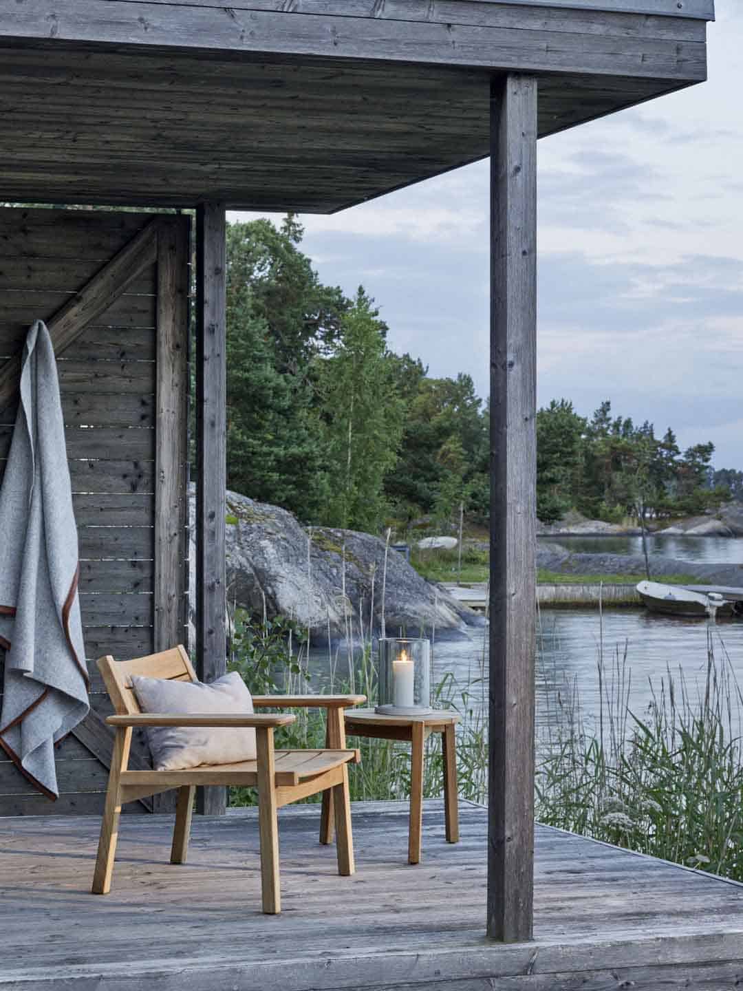 Кресло для отдыха и кофейный стол Skargaarden Djurö на деревянной террасе у воды
